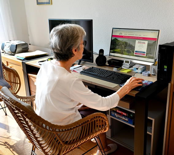Une femme âgée utilise son ordinateur dans son logement en résidence seniors Résidentiels
